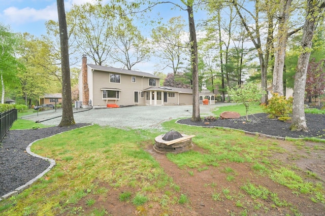 back of house featuring a fire pit and a chimney