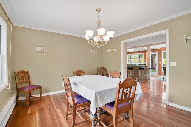dining room with light wood finished floors, a chandelier, ornamental molding, and baseboards