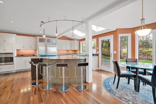 kitchen featuring appliances with stainless steel finishes, light wood-style flooring, white cabinets, vaulted ceiling, and recessed lighting