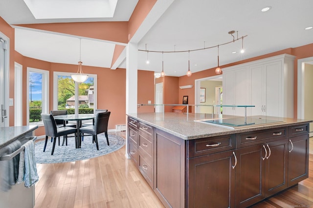kitchen with light wood-type flooring, black electric cooktop, pendant lighting, light stone counters, and recessed lighting
