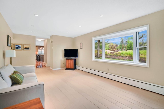 living area with baseboard heating, healthy amount of natural light, light wood-style floors, recessed lighting, and baseboards