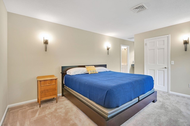 carpeted bedroom with baseboards and ensuite bath
