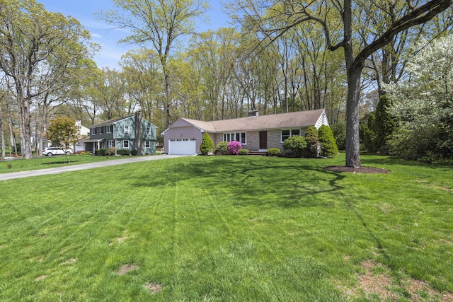 view of front of house with driveway, an attached garage, a front yard, and a chimney