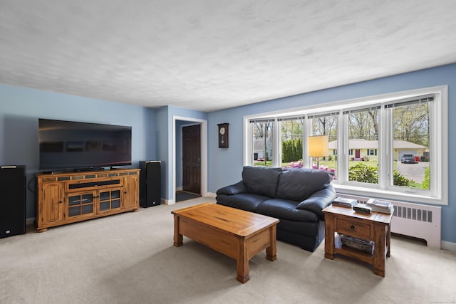 living area featuring light carpet, baseboards, and radiator