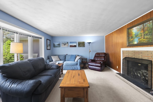living room featuring carpet, wood walls, a fireplace, and baseboards