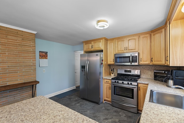 kitchen featuring stainless steel appliances, a sink, decorative backsplash, light brown cabinetry, and baseboards