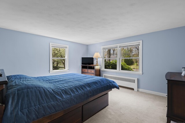bedroom featuring radiator, baseboards, and carpet