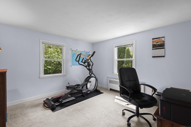 carpeted office space featuring radiator, plenty of natural light, and baseboards