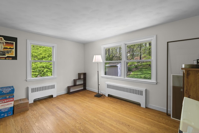 unfurnished room with radiator, light wood-style flooring, and baseboards