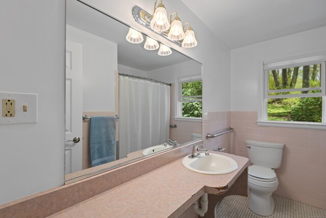 full bathroom with a sink, a chandelier, toilet, a wainscoted wall, and tile walls