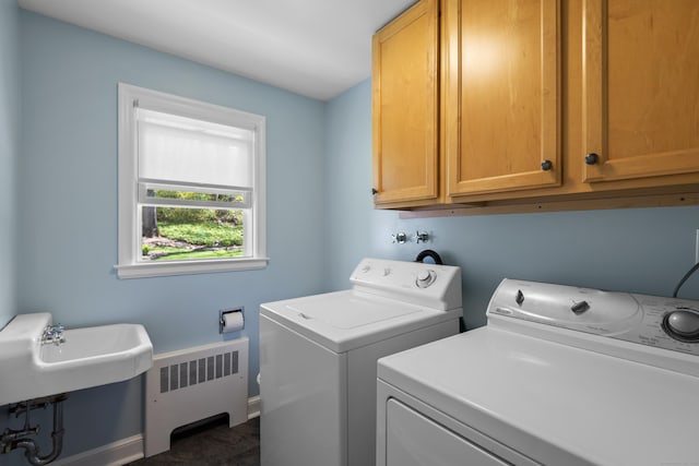 laundry area with radiator, cabinet space, washer and clothes dryer, and baseboards