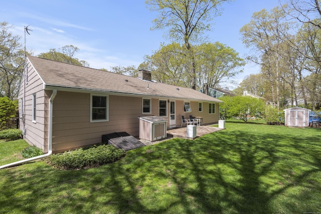 back of house with a shed, a patio area, a chimney, an outdoor structure, and a lawn