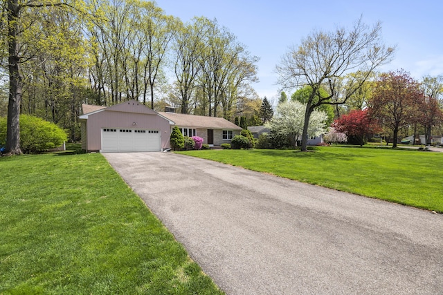 ranch-style home featuring an attached garage, driveway, a front lawn, and a chimney
