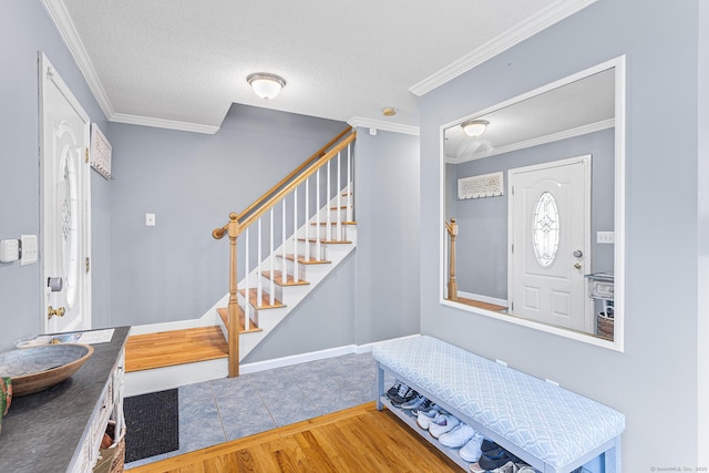 foyer featuring crown molding, stairs, tile patterned floors, and a textured ceiling