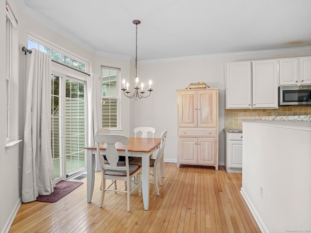 dining room with light wood-style flooring, crown molding, a chandelier, and baseboards