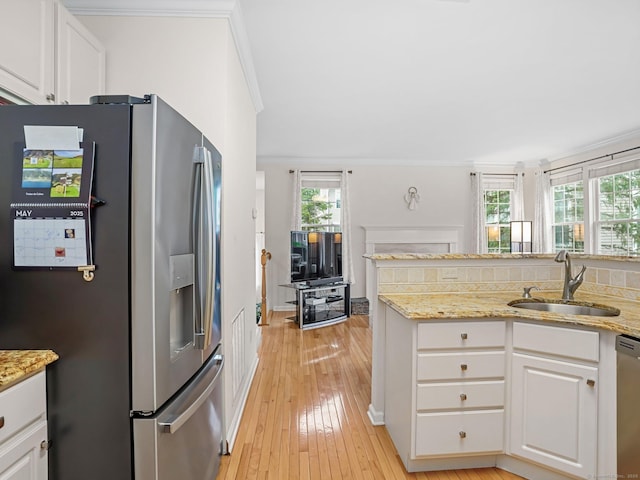 kitchen featuring appliances with stainless steel finishes, a sink, ornamental molding, light wood-style floors, and white cabinetry
