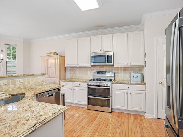 kitchen featuring appliances with stainless steel finishes, crown molding, white cabinets, light wood-style floors, and decorative backsplash