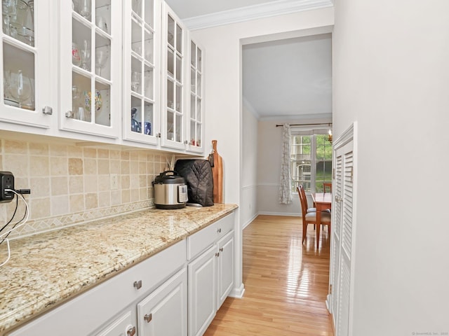 bar featuring crown molding, tasteful backsplash, light wood-style flooring, and baseboards