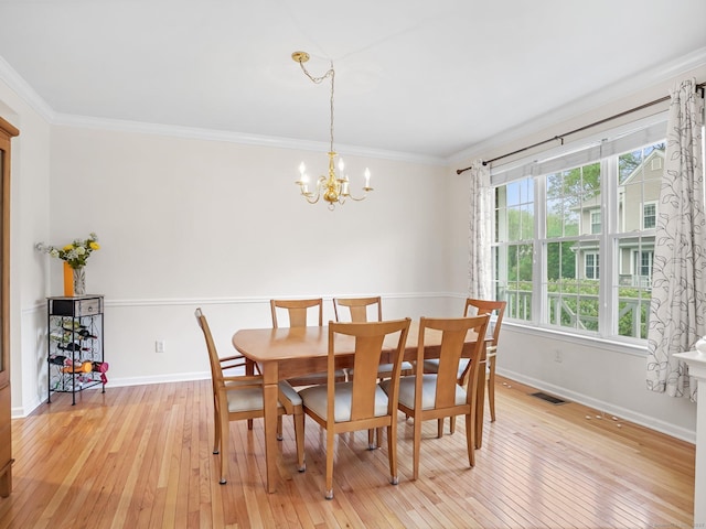 dining space featuring a chandelier, light wood-style flooring, baseboards, and crown molding
