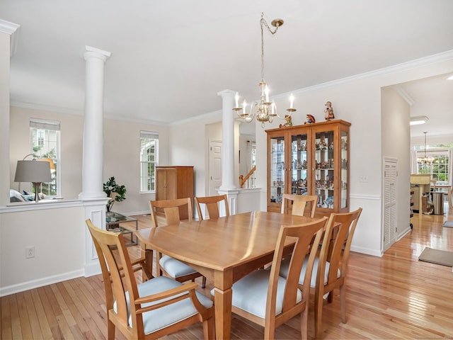 dining room featuring decorative columns, a chandelier, light wood-style flooring, healthy amount of natural light, and crown molding