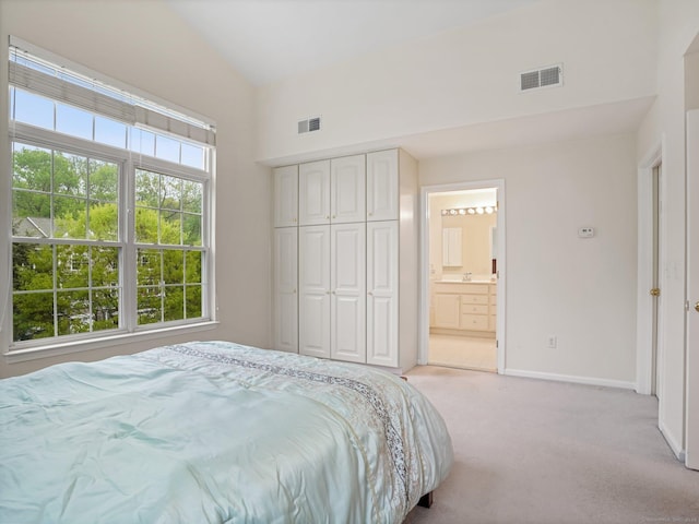 bedroom with light carpet, baseboards, a towering ceiling, connected bathroom, and a closet