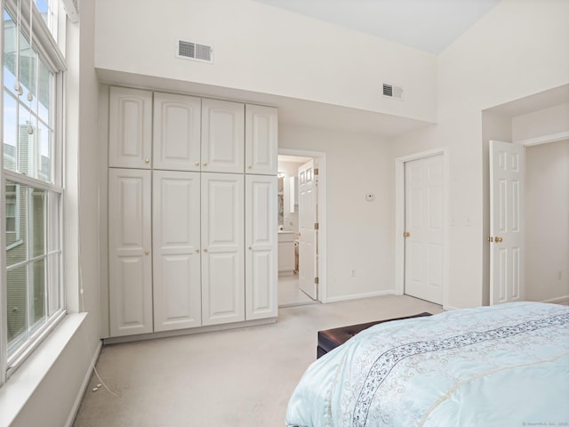 bedroom featuring multiple windows, baseboards, light carpet, and a towering ceiling