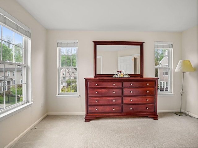 bedroom with multiple windows, light carpet, and baseboards