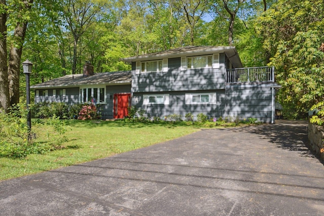 14 Live Oak Rd, Norwalk, CT 06851 - tri-level home with a chimney, a front yard, a balcony, and view of wooded area