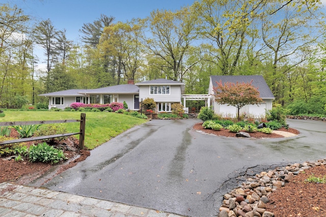 split level home featuring driveway, a front lawn, and a chimney
