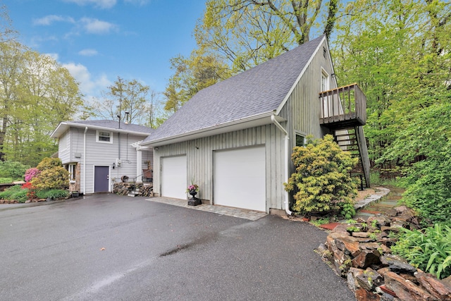 view of side of property featuring a shingled roof, stairway, a garage, and a deck