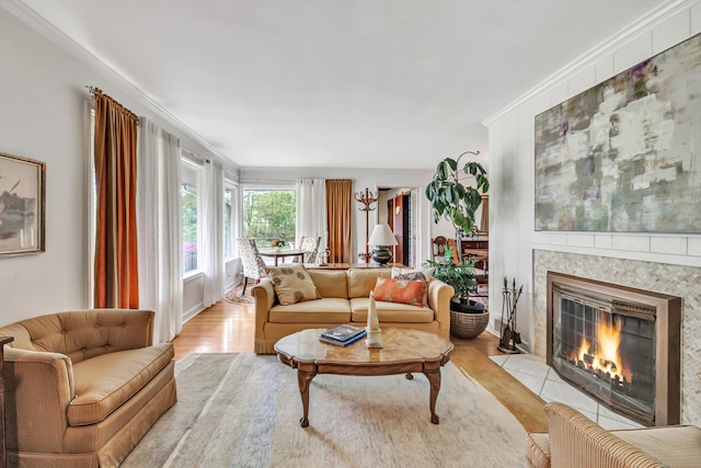 living room with light wood finished floors, a tile fireplace, and crown molding