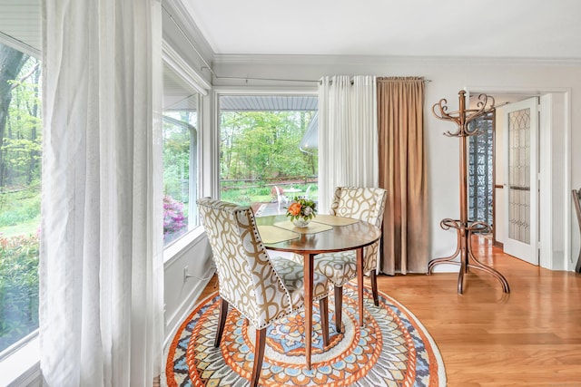 dining space with ornamental molding and wood finished floors