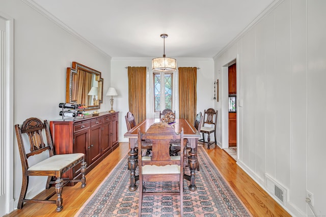dining space featuring light wood-style floors, ornamental molding, and baseboards