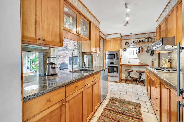 kitchen featuring a sink, stainless steel appliances, tasteful backsplash, glass insert cabinets, and dark stone counters
