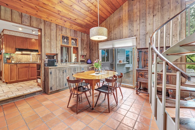 dining area with wooden ceiling, high vaulted ceiling, stairs, wooden walls, and light tile patterned flooring