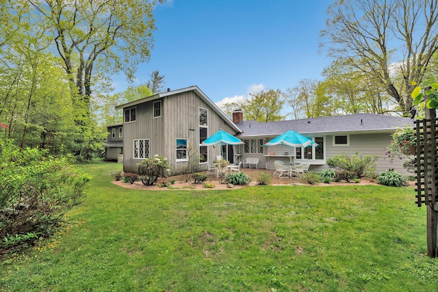 back of house featuring a patio, a yard, and a chimney
