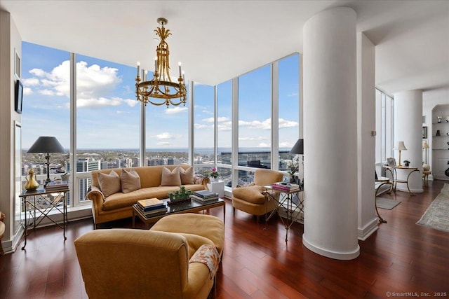 living room with hardwood / wood-style flooring, decorative columns, expansive windows, and a chandelier