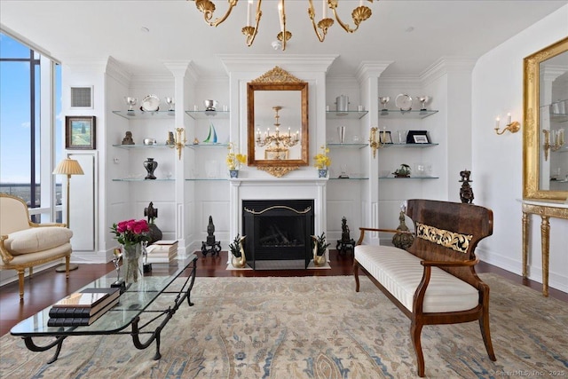 living room with built in features, wood finished floors, a fireplace with flush hearth, ornamental molding, and baseboards