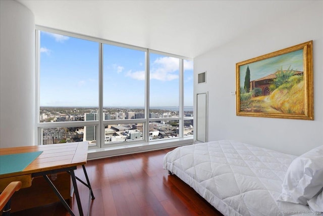 bedroom featuring a wall of windows and wood finished floors