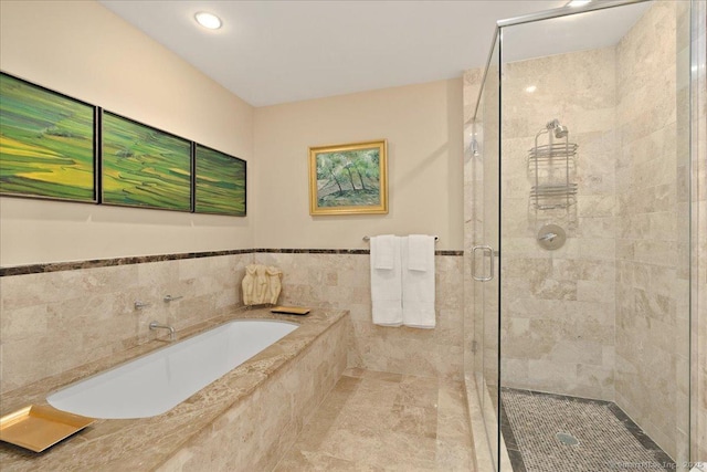 full bath with a shower stall, a garden tub, tile walls, recessed lighting, and a wainscoted wall