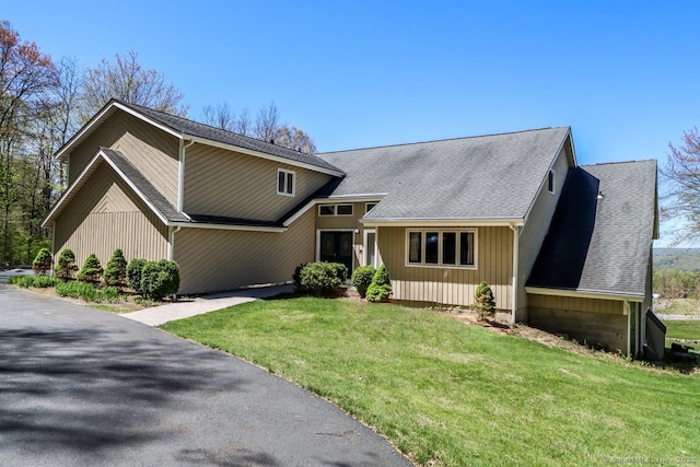 view of front of home featuring a front lawn and roof with shingles