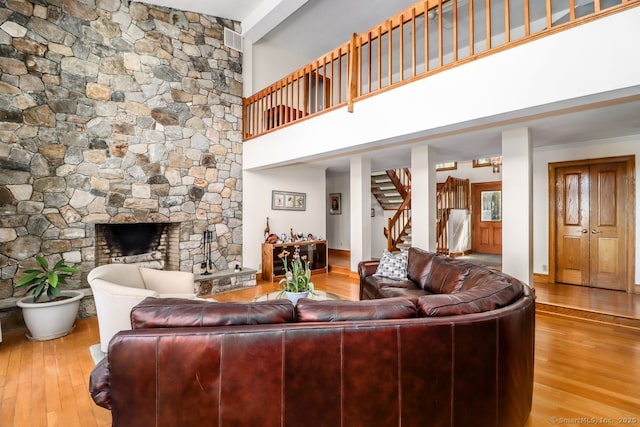 living room featuring stairs, a fireplace, a towering ceiling, and hardwood / wood-style flooring