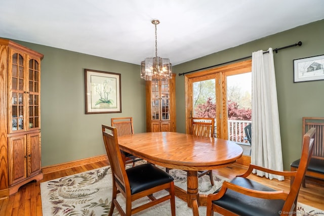 dining area with a chandelier, light wood-style flooring, and baseboards