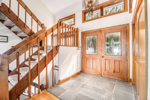 foyer entrance with an inviting chandelier, stairs, and stone tile flooring