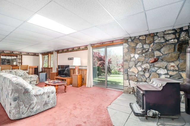 carpeted living area with a wood stove, plenty of natural light, and a paneled ceiling