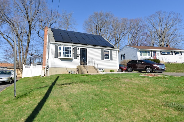 61 Kenyon Cir, New Britain, CT 06053 - view of front of property with roof mounted solar panels, fence, a front lawn, and a chimney