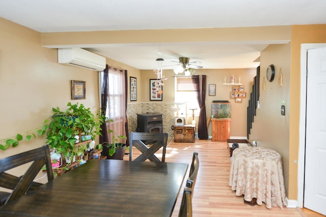 61 Kenyon Cir, New Britain, CT 06053 - dining area featuring a wall mounted air conditioner, a wood stove, ceiling fan, baseboards, and light wood-style floors
