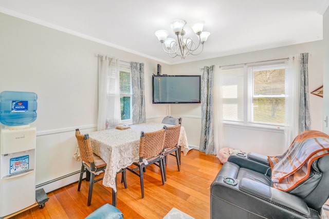 dining space featuring a baseboard heating unit, a chandelier, light wood-style flooring, and crown molding