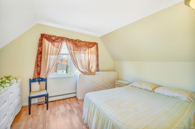 bedroom with a baseboard heating unit, vaulted ceiling, and light wood-style floors