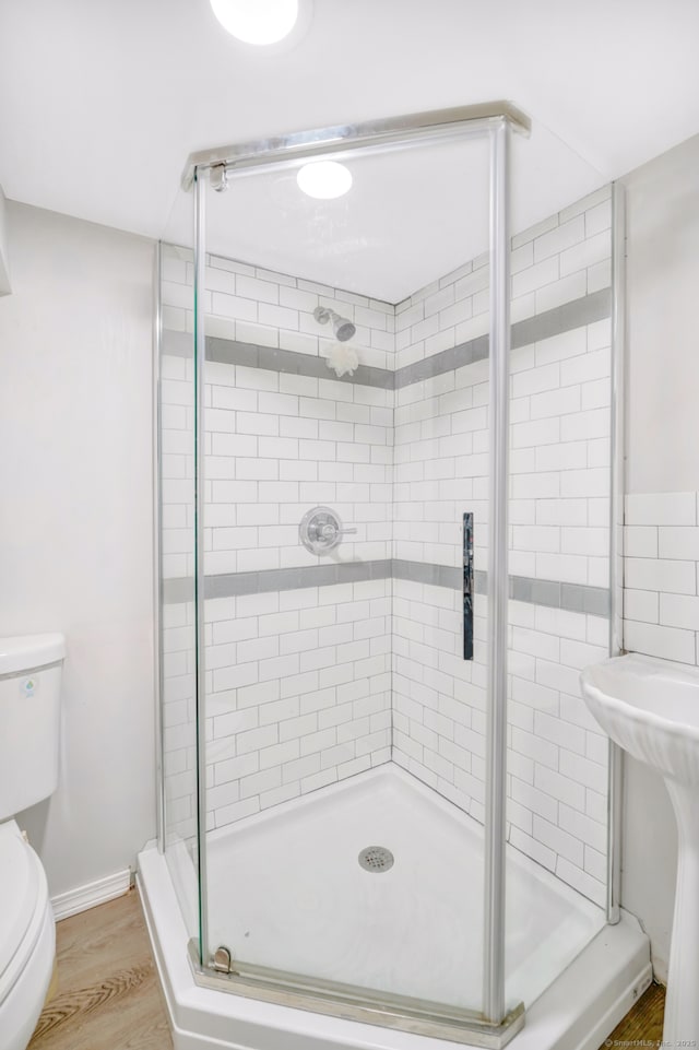 bathroom featuring toilet, a stall shower, and wood finished floors
